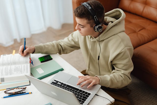 Notizen machender Student bei der Teilnahme an einem online-Kurs per Laptop