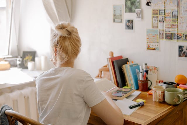 student sitting in front of a desk in student dorm room