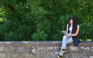 Female student sitting on a wall looking for jobs in Germany using an Ipad