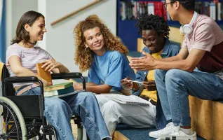 Studierende im Rollstuhl redet fröhlich mit Kommilitonen im Studium mit Behinderung