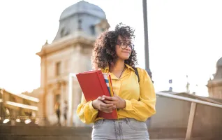 University student in yellow jacket holding books