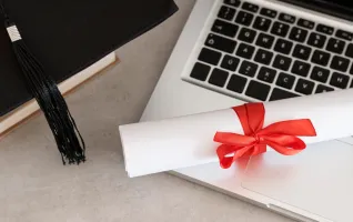 Distance learning university diploma next to a laptop