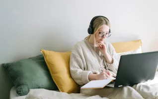 Woman with laptop taking notes while in distance learning studies