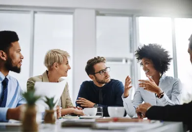 Studierende im Master MBA sitzen an einem Konferenztisch in einem hellen Büro und diskutieren in der Praxis über die Inhalte aus dem Studium an der PFH Göttingen.