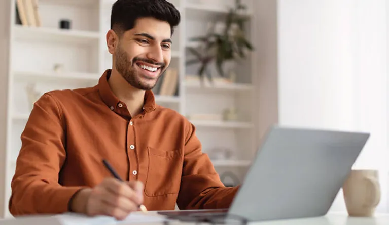 Student sieht sich am Laptop Inhalte des Master Wirtschaftspsychologie Fernstudiums an 