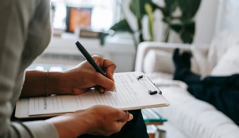 woman writing on a clipboard during therapy session