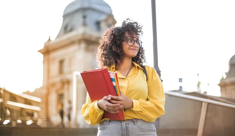 University student in yellow jacket holding books