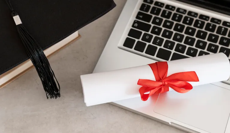 Distance learning university diploma next to a laptop